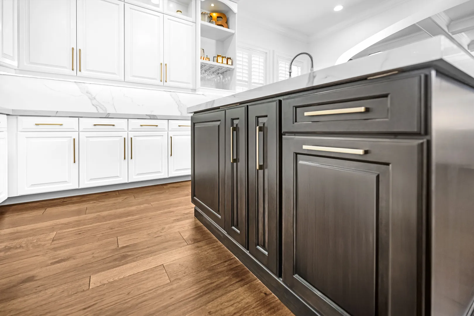 Kitchen remodel with white cabinets, a dark island, marble countertops and gold hardware