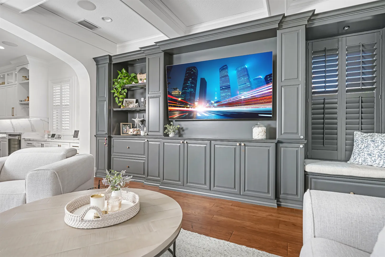 Gray built-in media wall and cabinetry with open shelves and shutters