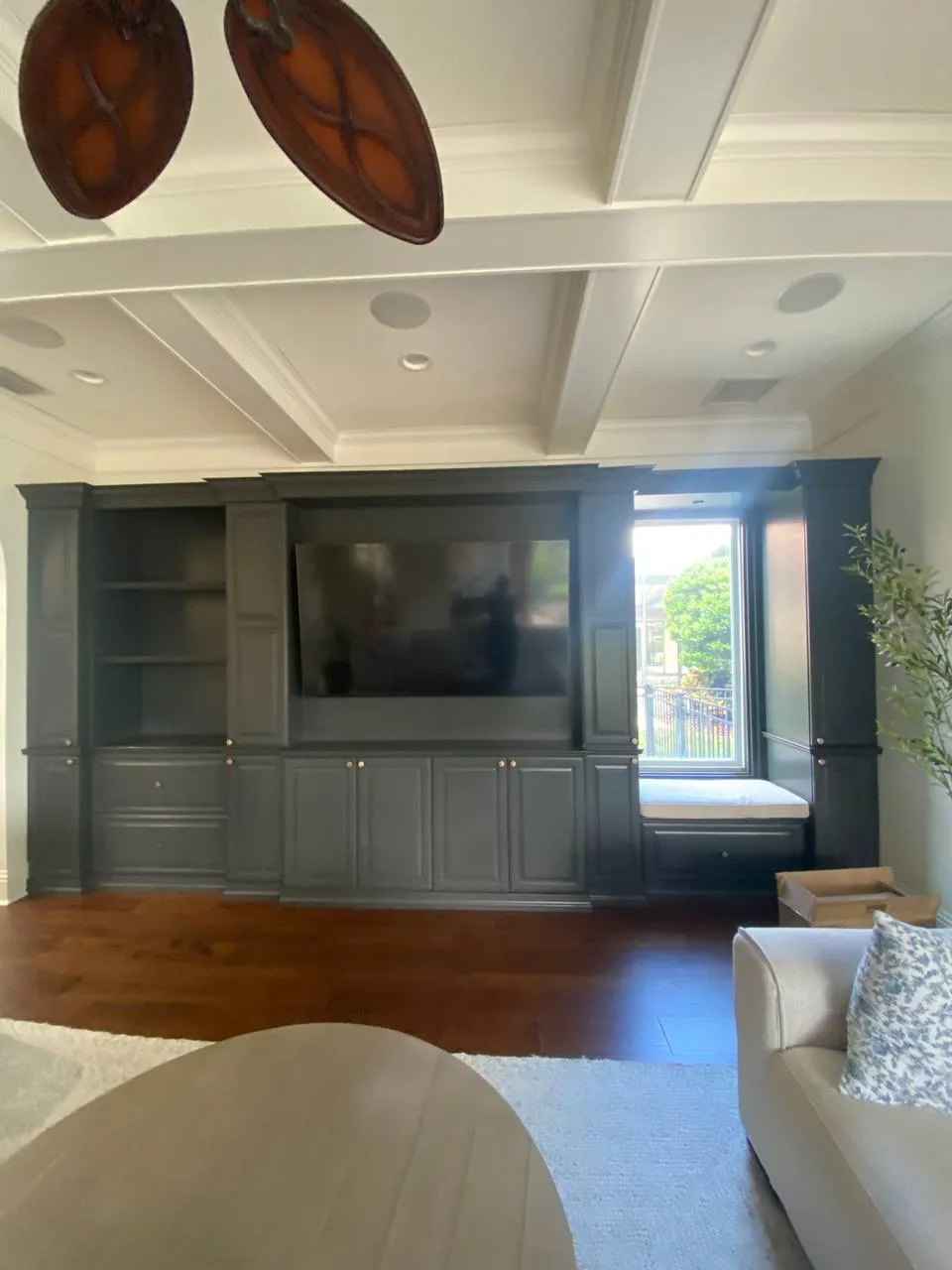 Gray built-in media wall with a TV and window seat before restyling