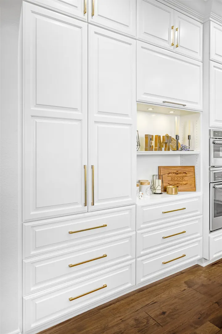 Finished white kitchen cabinets with gold hardware and an open prep shelf