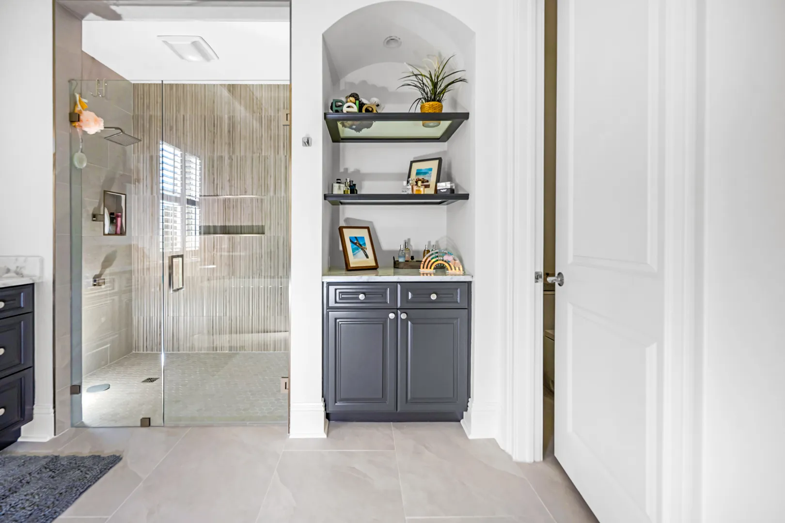 Bathroom with a dark gray vanity, marble counter and a glass walk-in shower