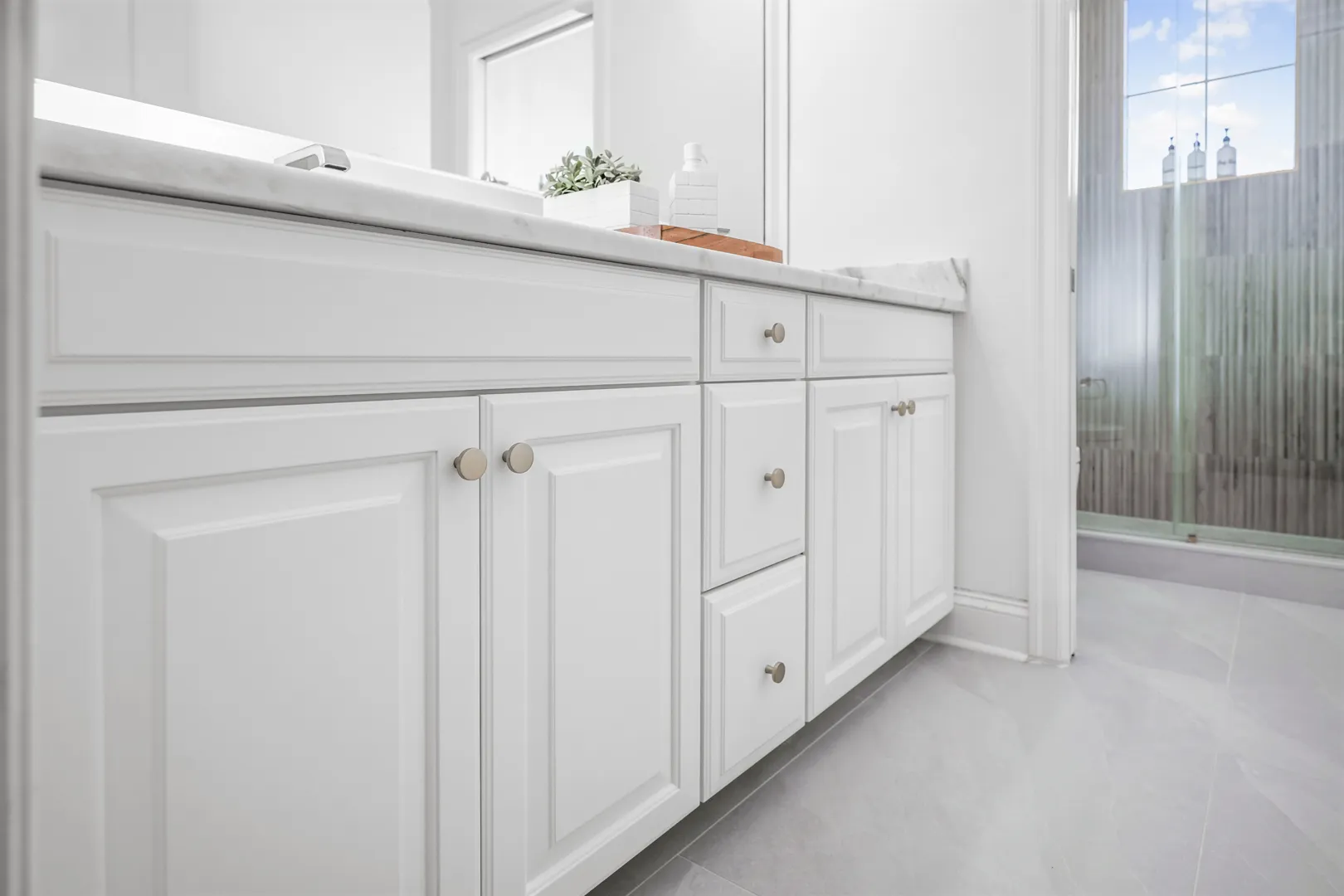 Bathroom remodel with a white vanity, marble counter and a glass shower