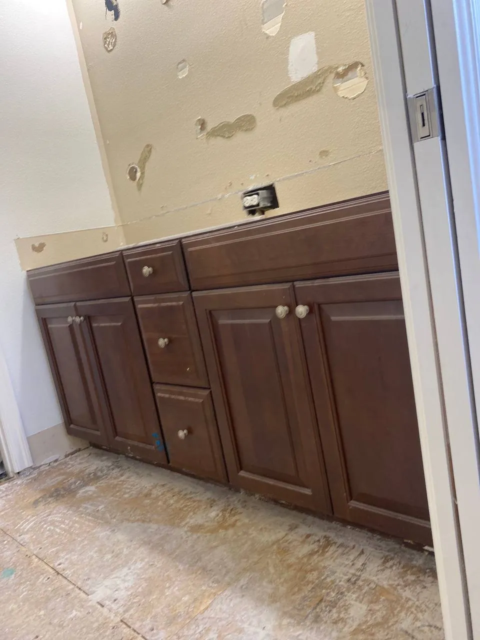 Dark wood bathroom cabinets and patched drywall during a remodel