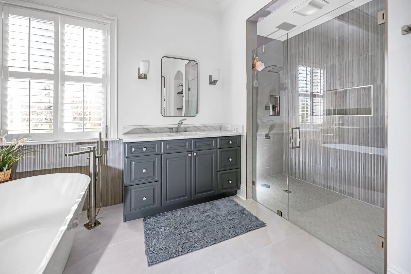 Primary bathroom with a navy vanity, a freestanding tub and a glass shower