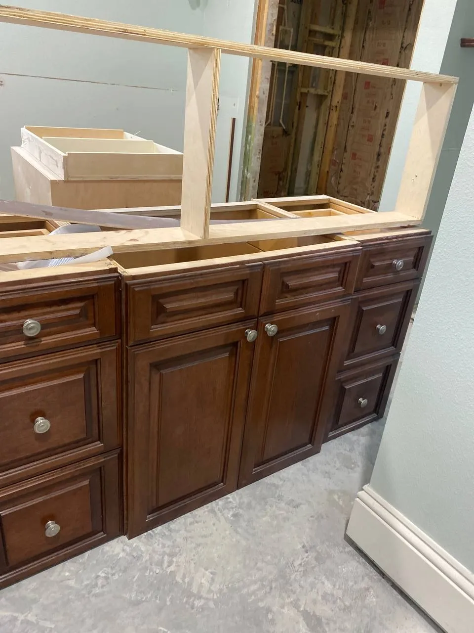 Dark wood bathroom vanity with a rough mirror frame during construction