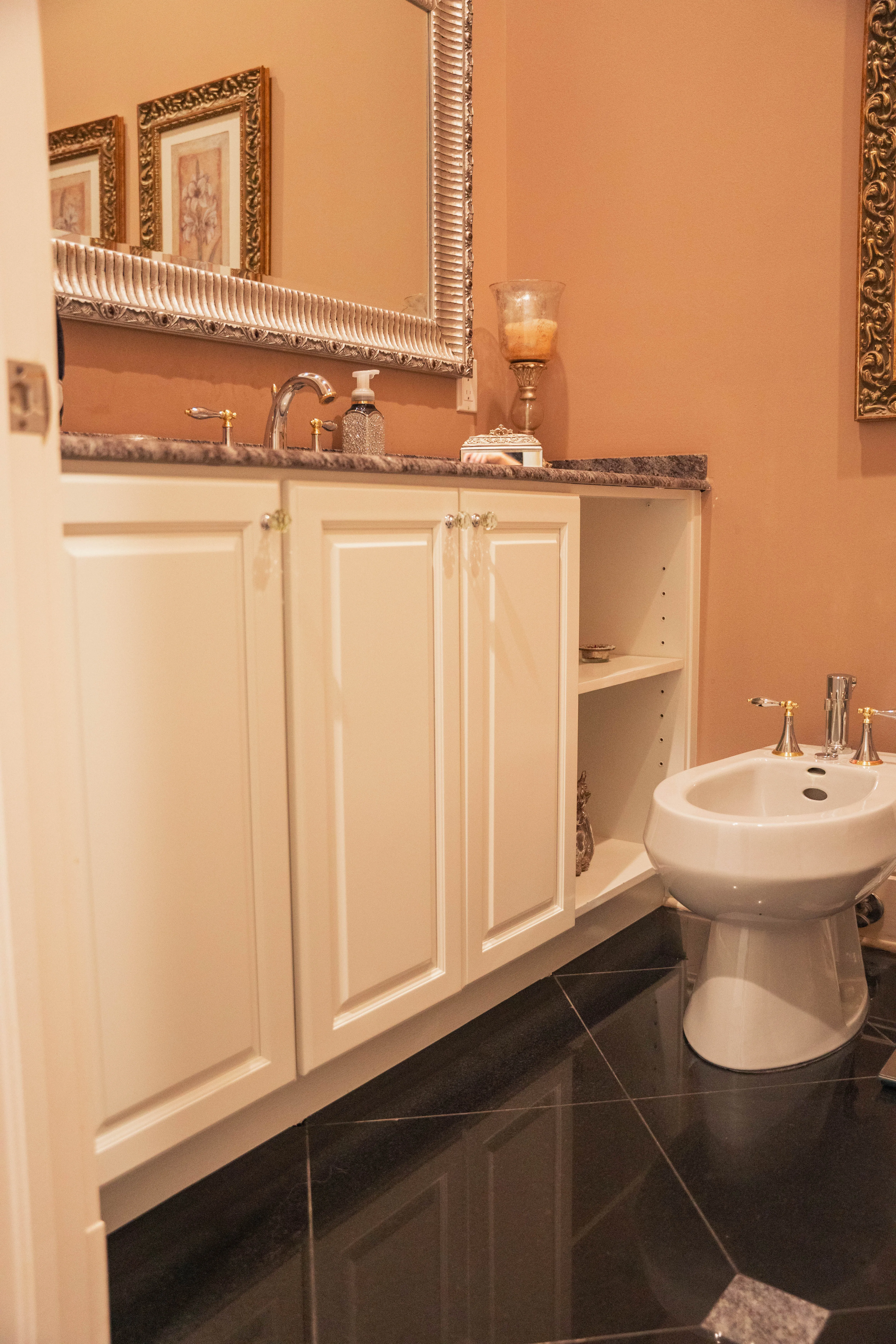 Bathroom remodel with white vanity cabinets, a marble countertop and a bidet