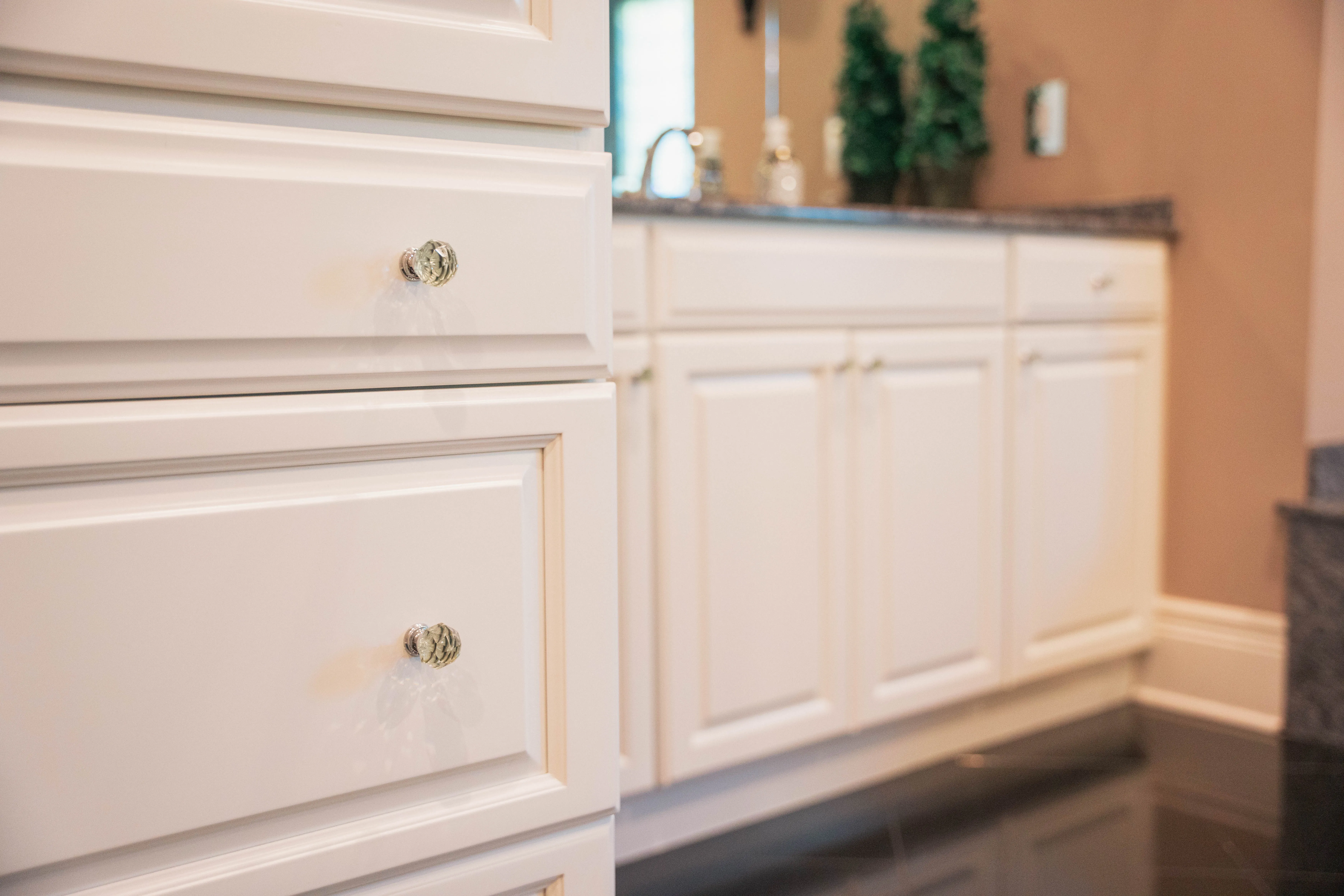 Close-up of freshly painted white bathroom cabinet drawers with crystal knobs