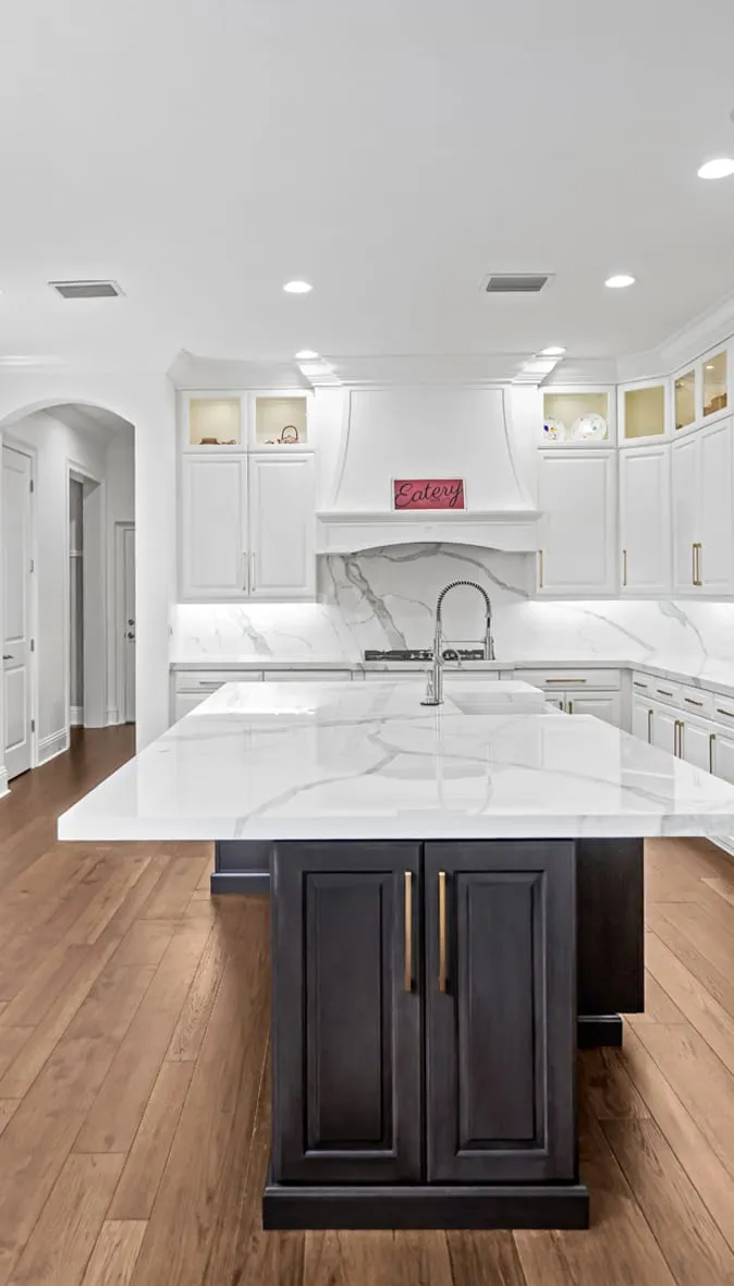 New hardwood flooring in a white kitchen with a dark island