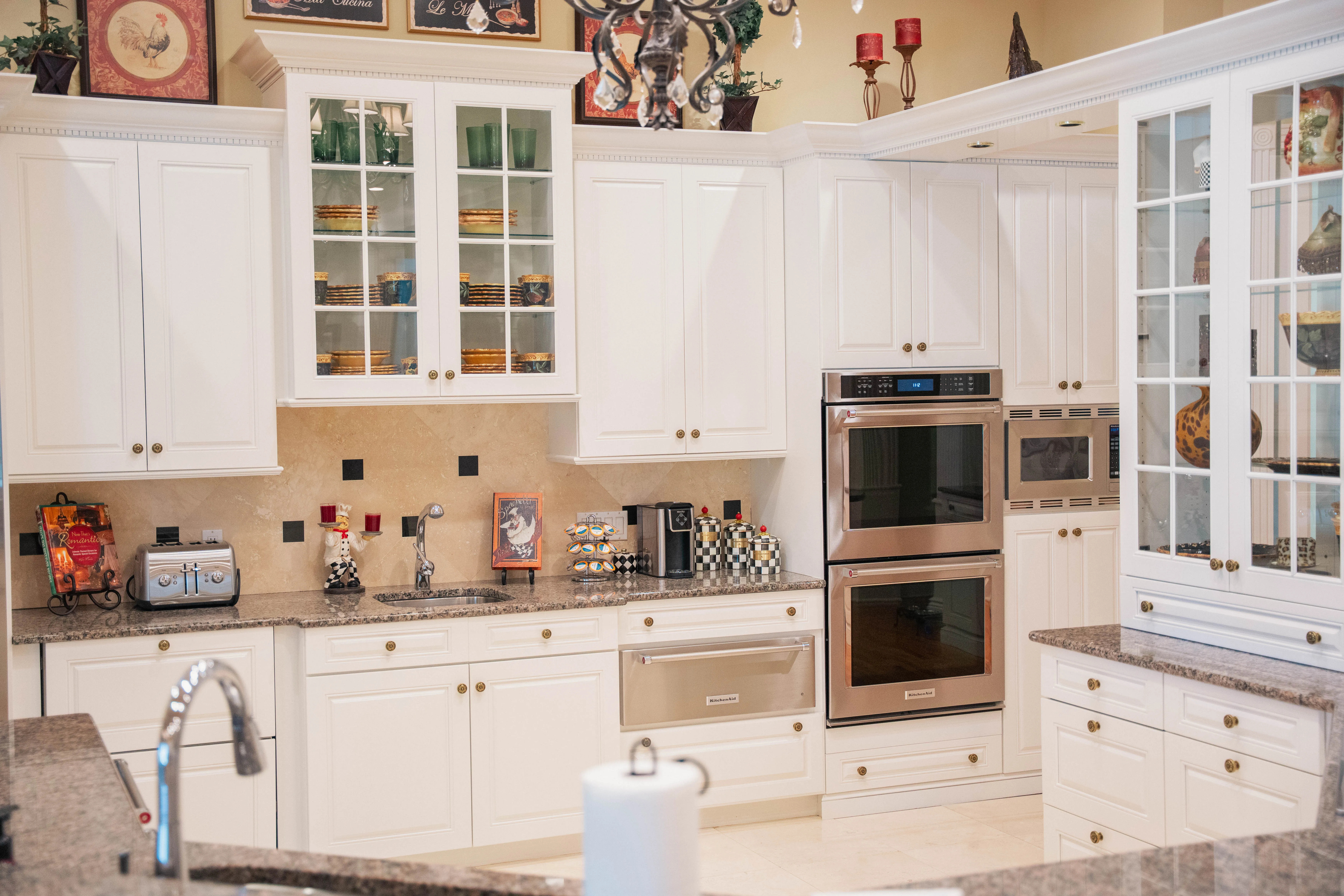Kitchen remodel with white cabinetry, glass-front upper cabinets and stainless double ovens