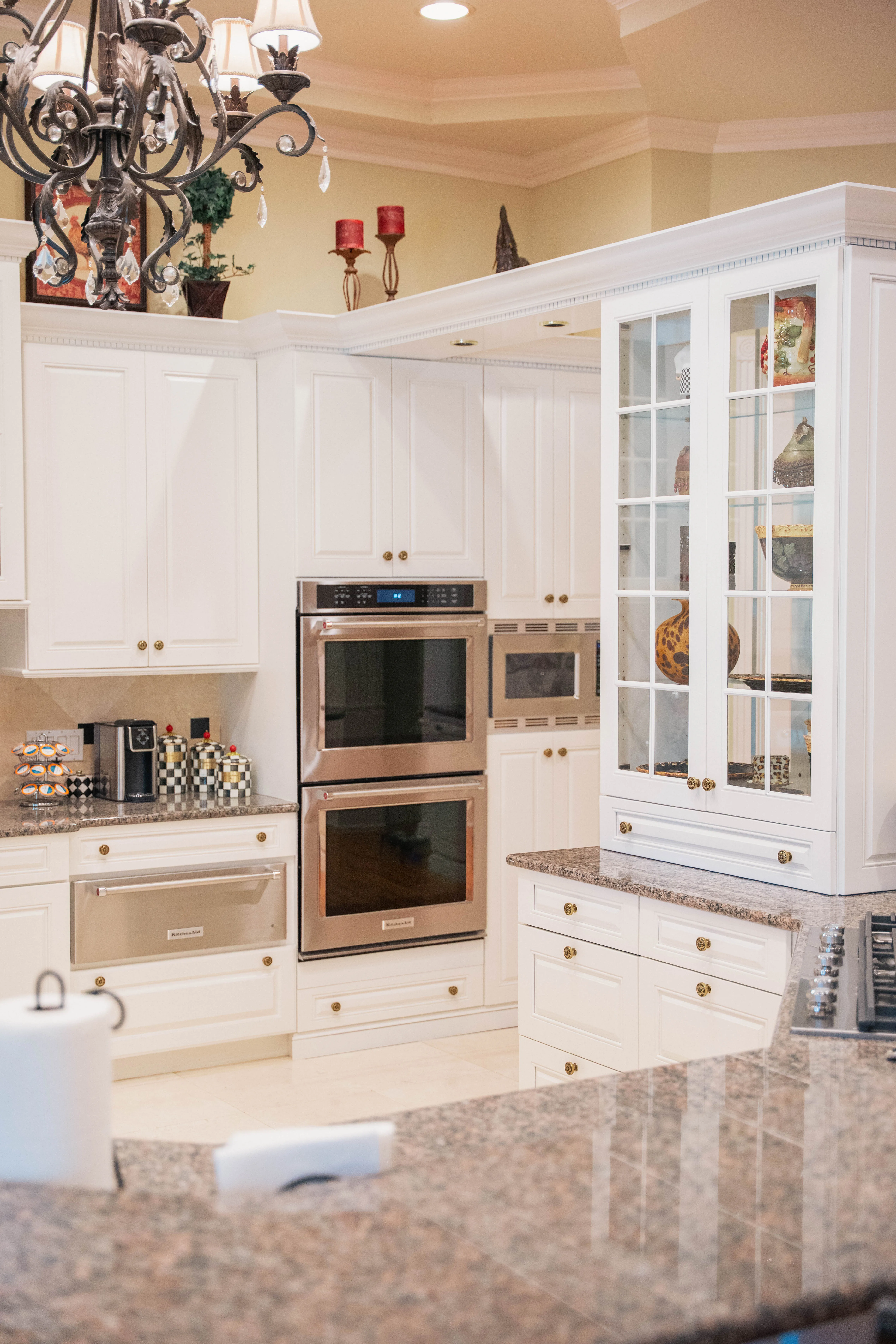 Kitchen remodel with a white glass-front display hutch, stainless wall ovens and granite counters