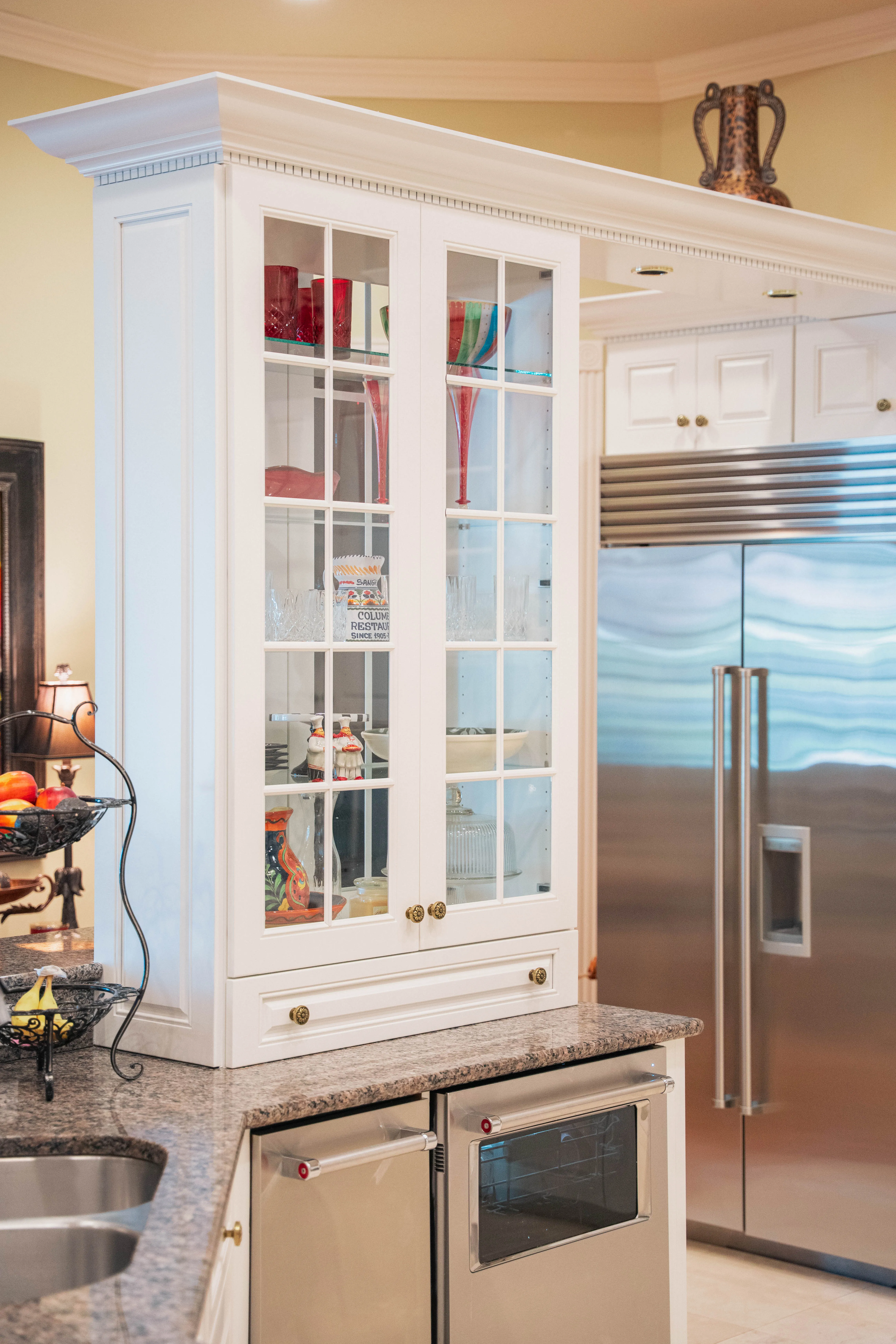 Kitchen remodel with a white glass-front cabinet beside a stainless steel refrigerator