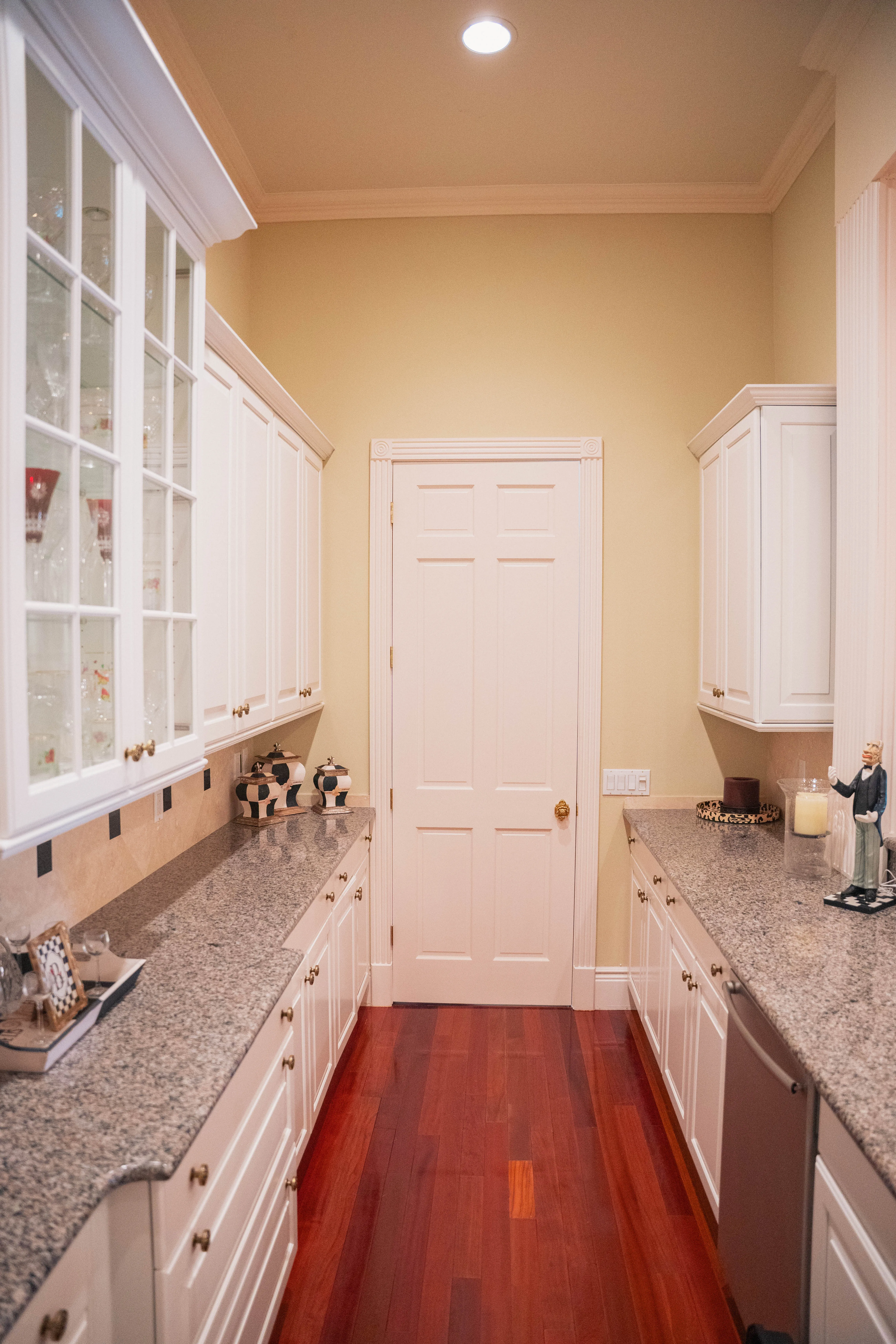 Galley kitchen remodel with white cabinets, granite counters and hardwood flooring