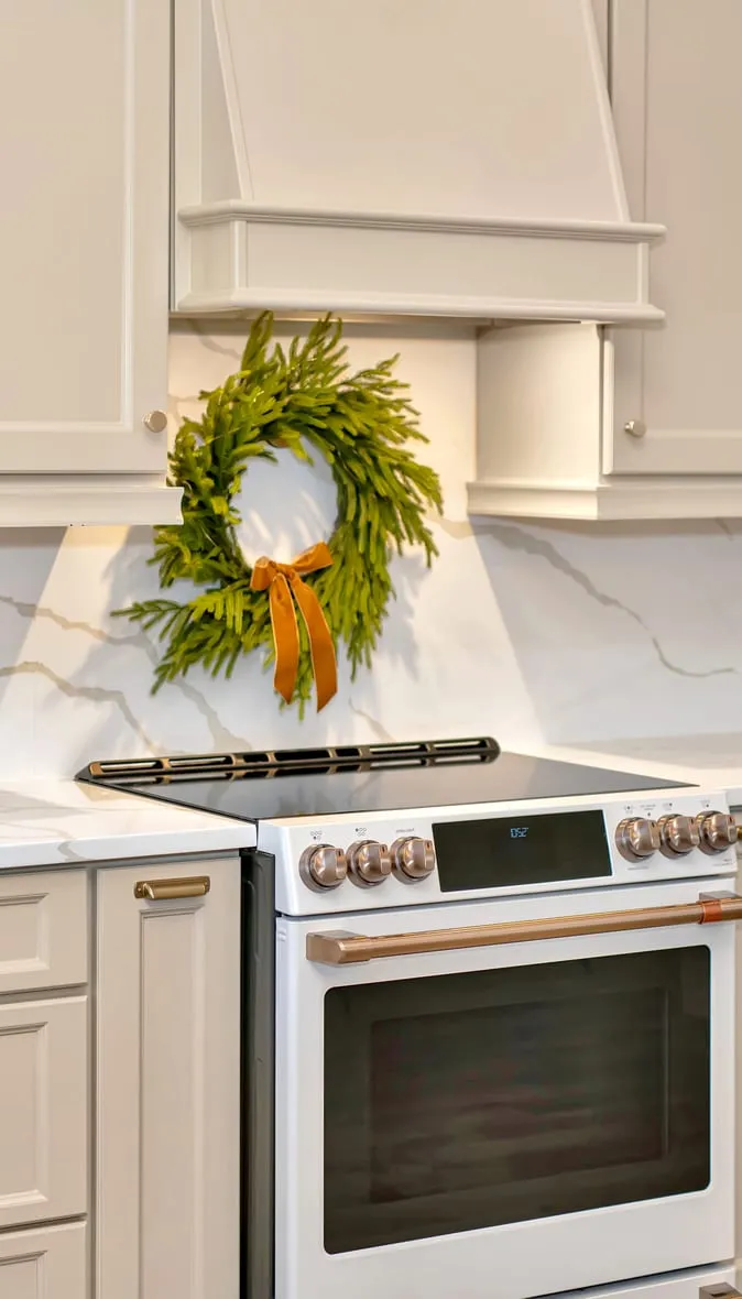 Freshly painted cream kitchen cabinets with brass hardware and a quartz backsplash