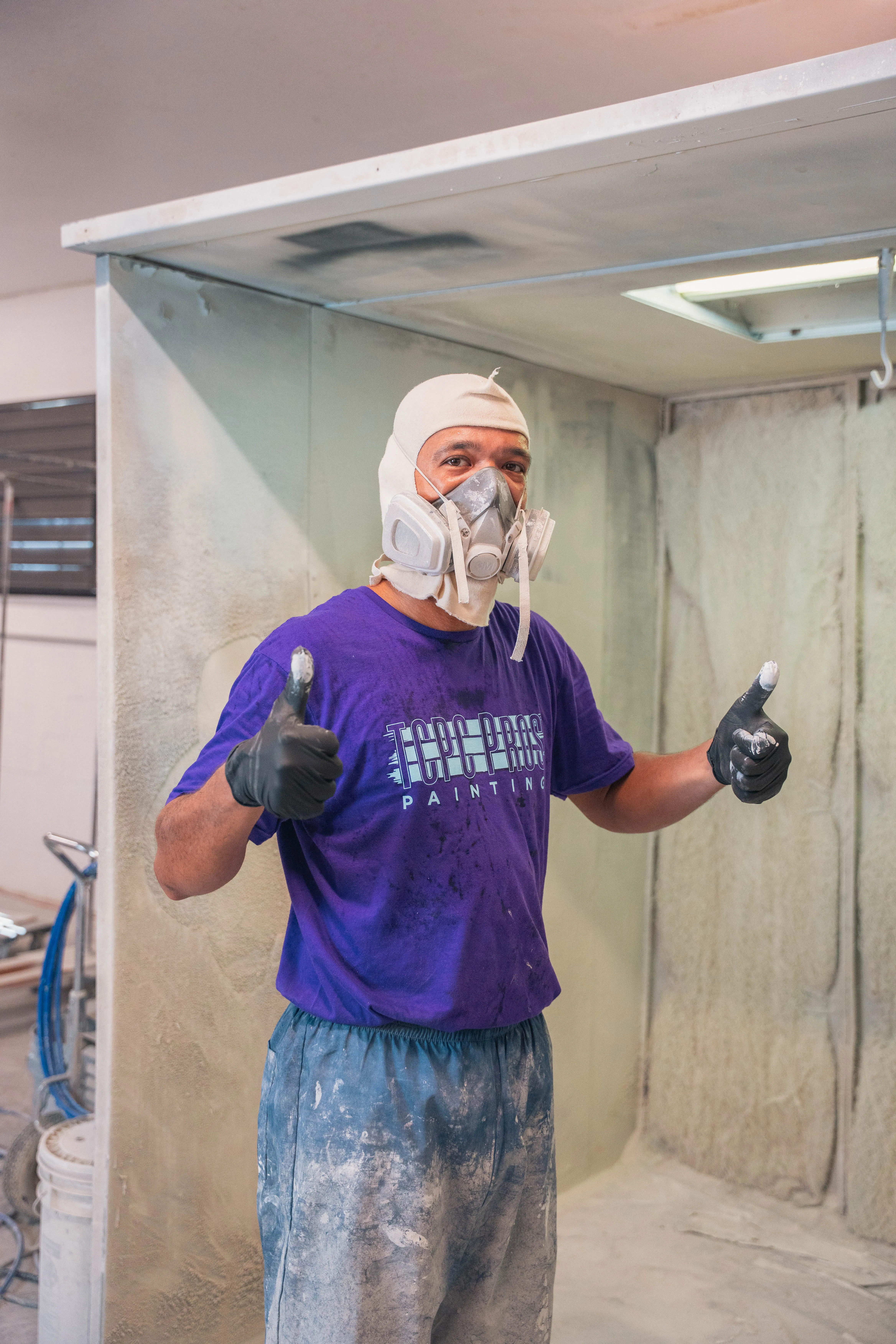 Cabinet painter in a spray booth giving a thumbs up