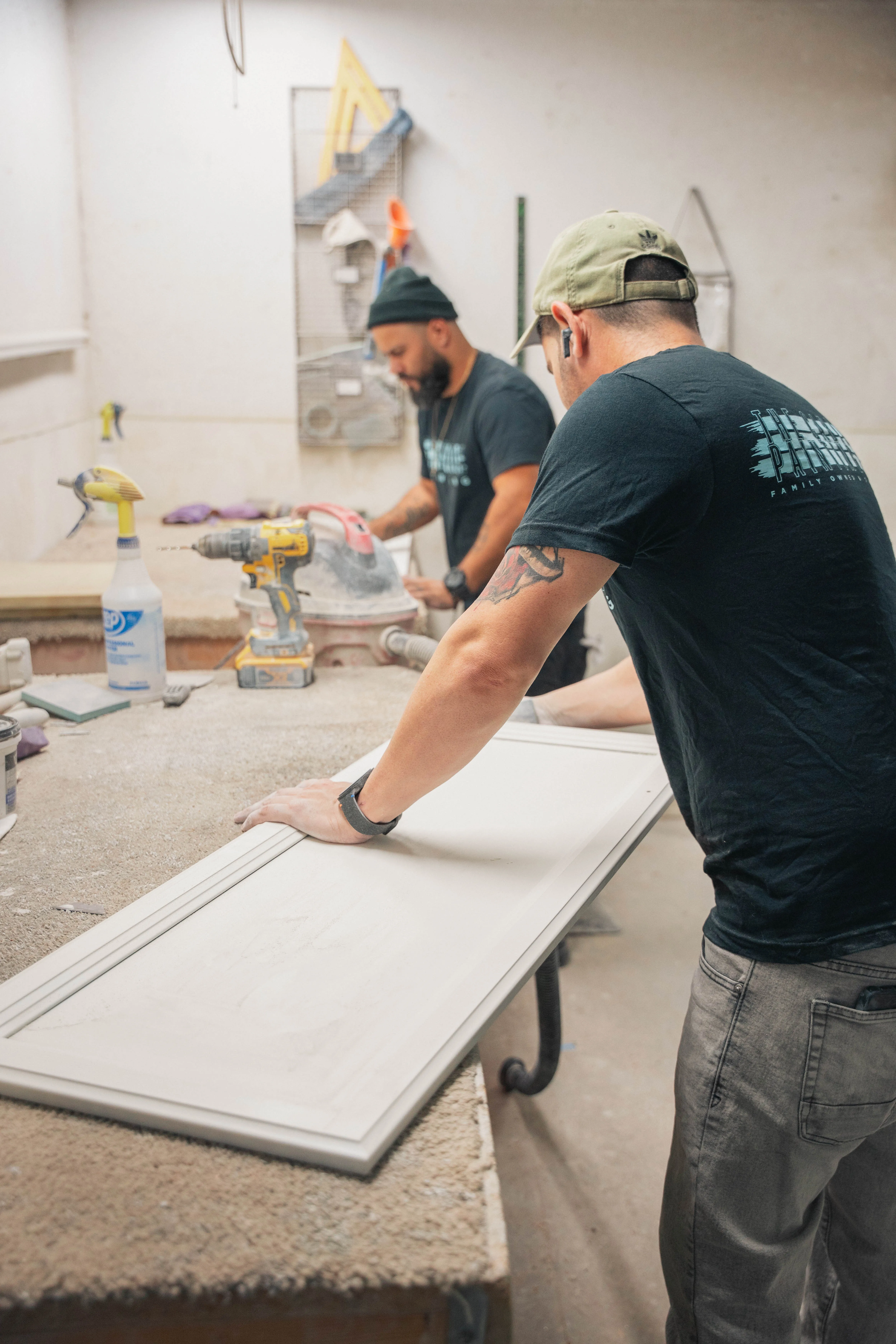 Two crew members preparing cabinet doors at a workbench